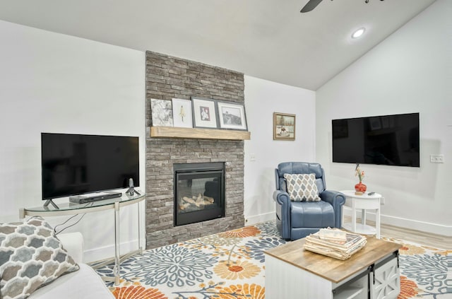 living room featuring baseboards, ceiling fan, a fireplace, and vaulted ceiling