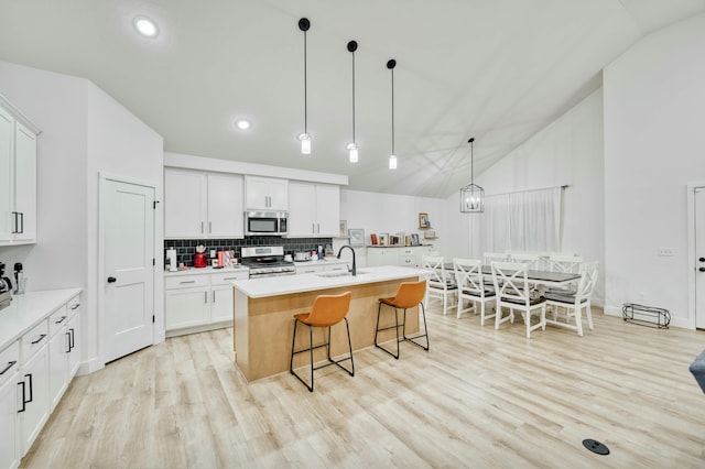 kitchen with a kitchen bar, a center island with sink, a sink, stainless steel appliances, and decorative backsplash