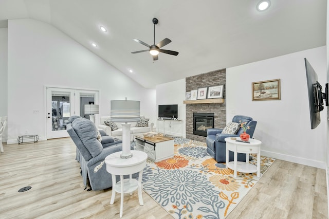 living area featuring light wood finished floors, a fireplace, high vaulted ceiling, and a ceiling fan