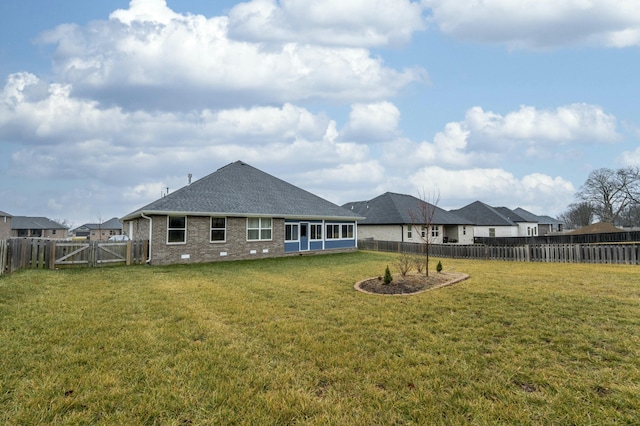 back of property with brick siding, a fenced backyard, a lawn, and a gate