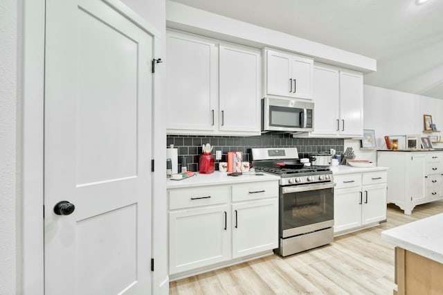 kitchen with light wood-style floors, stainless steel appliances, tasteful backsplash, and white cabinets