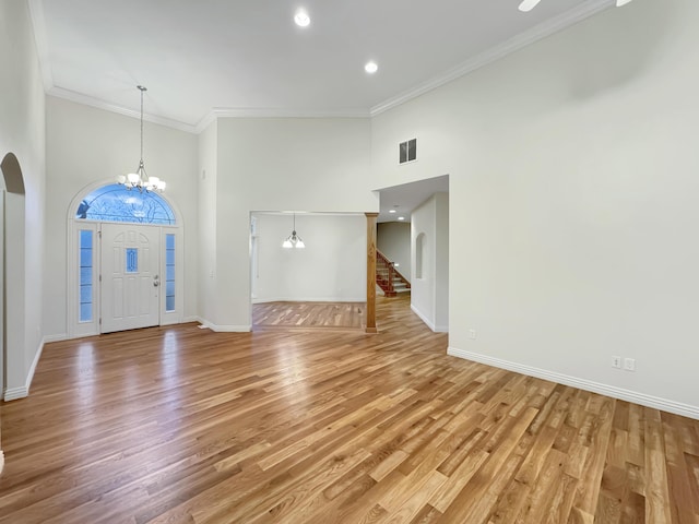 entryway featuring a high ceiling, ornamental molding, wood-type flooring, and a chandelier