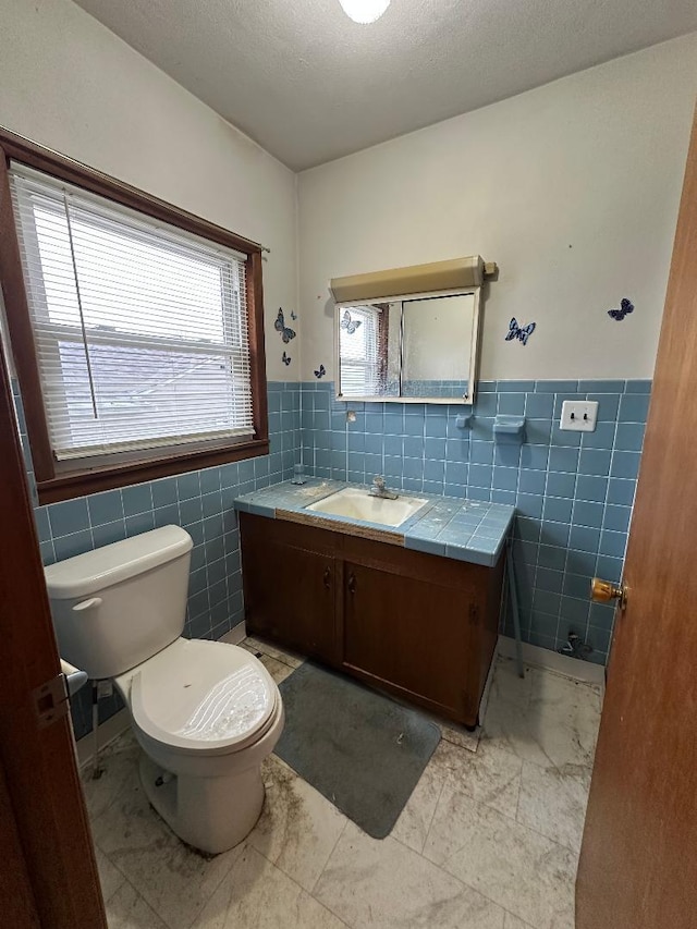 bathroom with vanity, tile walls, a textured ceiling, and toilet