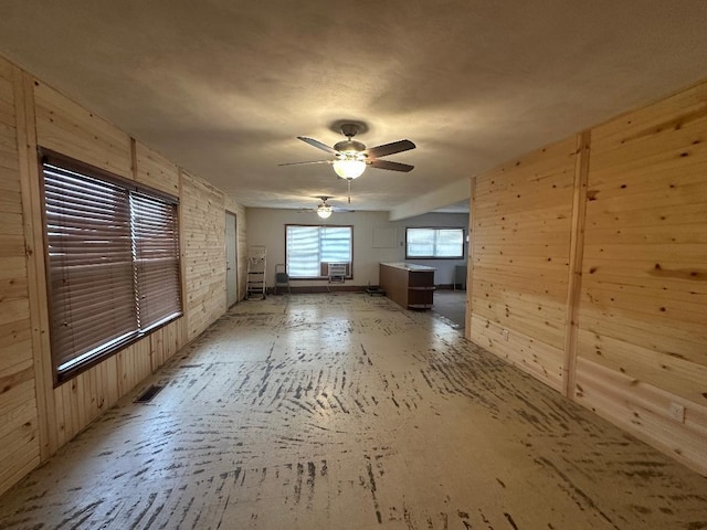 unfurnished room featuring wooden walls and ceiling fan