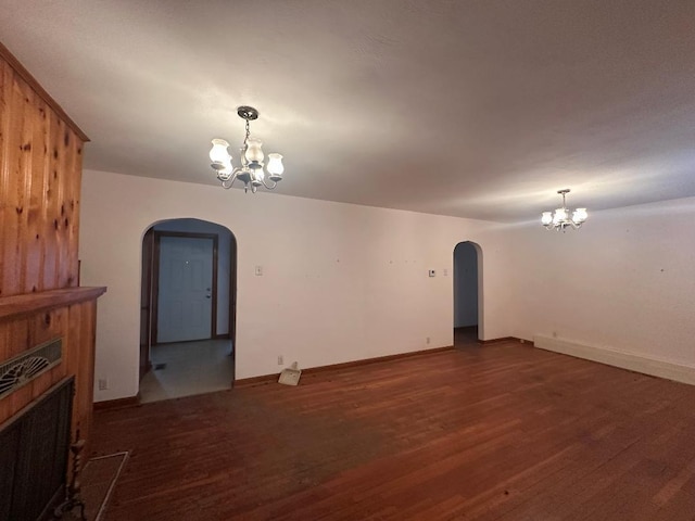 unfurnished living room with an inviting chandelier and dark hardwood / wood-style flooring