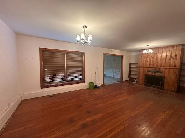 unfurnished living room with a notable chandelier, dark wood-type flooring, and a fireplace