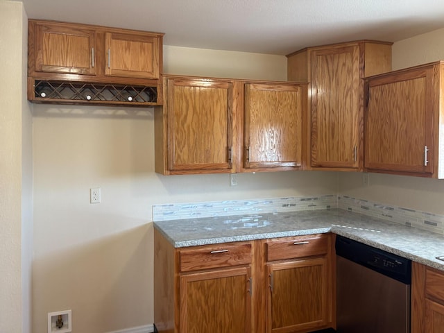 kitchen with light stone counters, backsplash, and stainless steel dishwasher