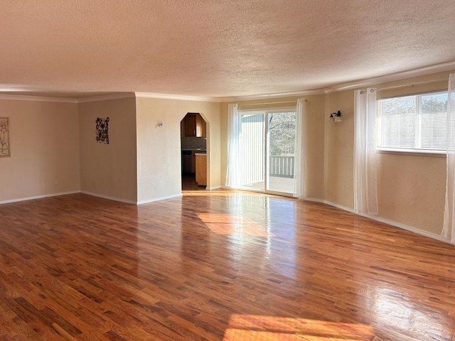 spare room featuring crown molding, hardwood / wood-style floors, and a textured ceiling