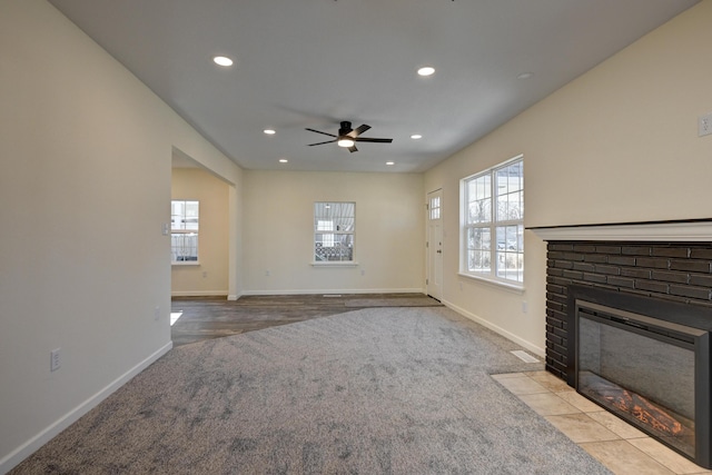 unfurnished living room featuring ceiling fan, a brick fireplace, and light carpet