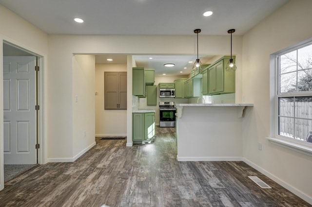 kitchen featuring dark wood-type flooring, light stone counters, kitchen peninsula, green cabinets, and stainless steel appliances