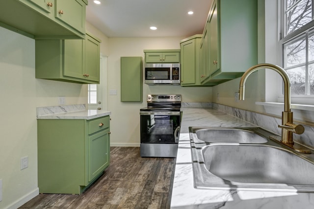 kitchen featuring sink, green cabinets, dark hardwood / wood-style floors, and appliances with stainless steel finishes