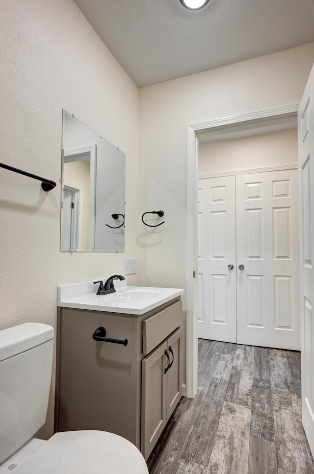 bathroom featuring vanity, hardwood / wood-style floors, a textured ceiling, and toilet