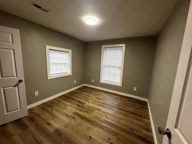 spare room with a textured ceiling and dark hardwood / wood-style flooring