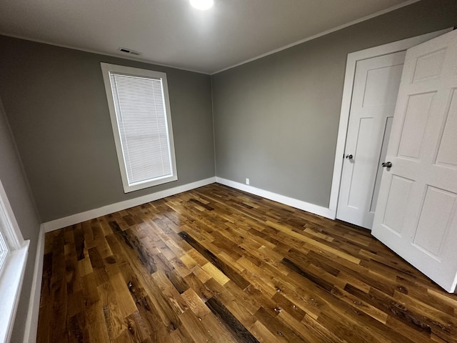 empty room featuring crown molding and dark hardwood / wood-style floors