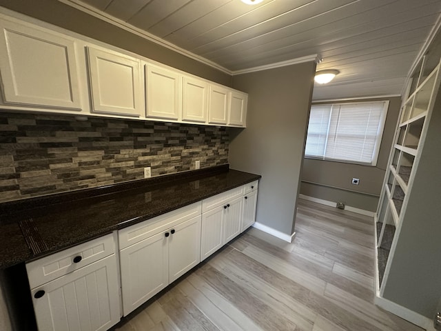 kitchen featuring white cabinetry, backsplash, ornamental molding, and dark stone counters