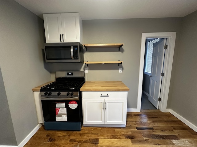 kitchen with appliances with stainless steel finishes, dark hardwood / wood-style flooring, wooden counters, and white cabinets