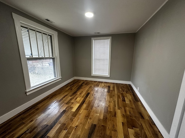 spare room with ornamental molding and dark hardwood / wood-style flooring