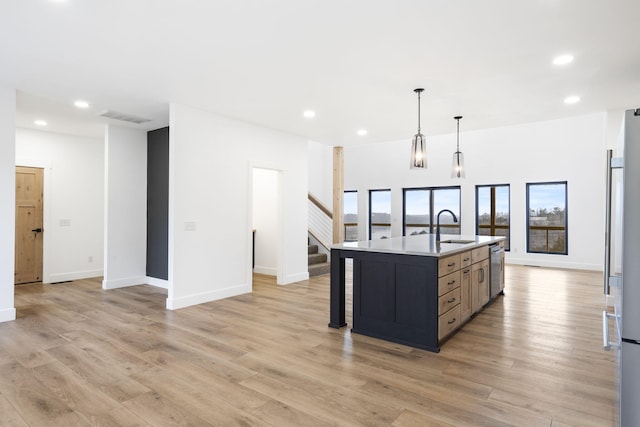 kitchen with sink, hanging light fixtures, light hardwood / wood-style flooring, dishwasher, and an island with sink