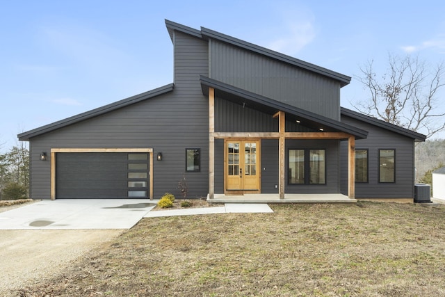 contemporary home featuring cooling unit, a garage, and a front lawn