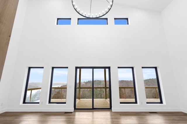 doorway with hardwood / wood-style flooring, a wealth of natural light, a high ceiling, and a notable chandelier