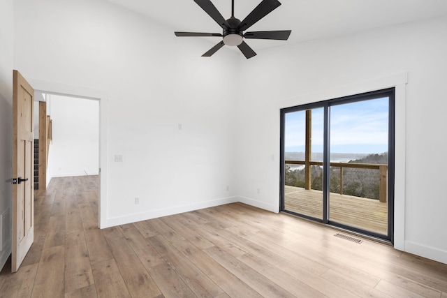 unfurnished room with a high ceiling, ceiling fan, and light wood-type flooring