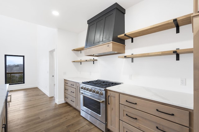 kitchen with high end stainless steel range oven, dark hardwood / wood-style floors, custom exhaust hood, and light stone counters