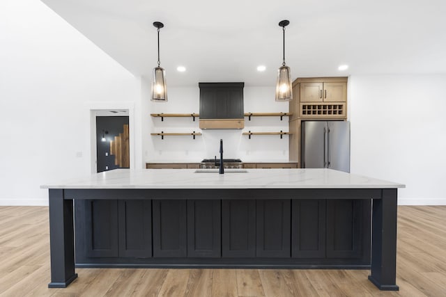 kitchen featuring light stone counters, appliances with stainless steel finishes, and a large island with sink