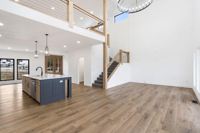 kitchen featuring a healthy amount of sunlight, a kitchen island with sink, pendant lighting, and light hardwood / wood-style floors