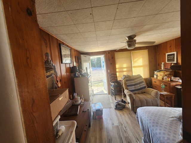 interior space featuring wooden walls, ceiling fan, and light wood-type flooring