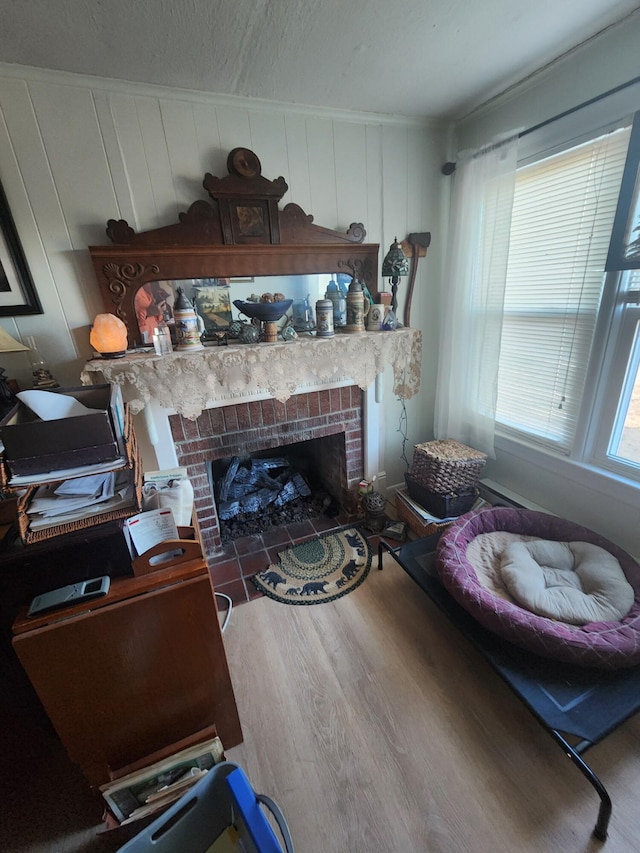 living room with a brick fireplace, crown molding, hardwood / wood-style floors, and a textured ceiling