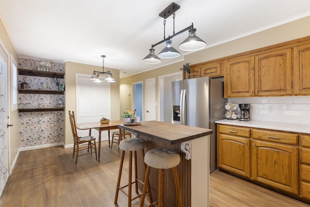 kitchen featuring decorative light fixtures, light hardwood / wood-style floors, a breakfast bar area, and backsplash