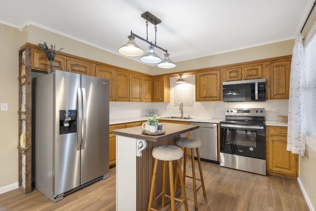 kitchen featuring sink, a center island, appliances with stainless steel finishes, hardwood / wood-style floors, and backsplash