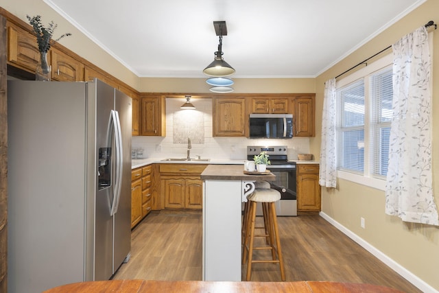 kitchen featuring a kitchen island, sink, a breakfast bar area, hanging light fixtures, and stainless steel appliances