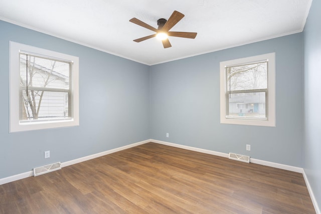 spare room with crown molding, a healthy amount of sunlight, and wood-type flooring