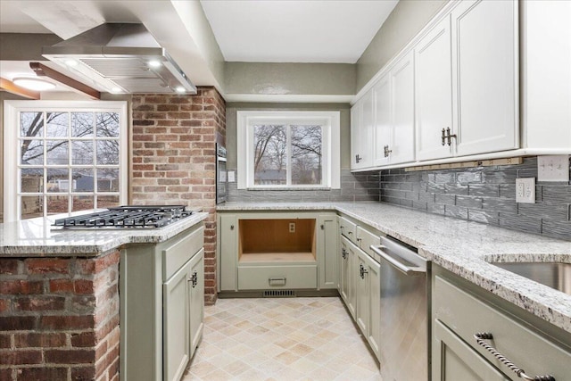 kitchen featuring stainless steel appliances, tasteful backsplash, island range hood, and light stone counters