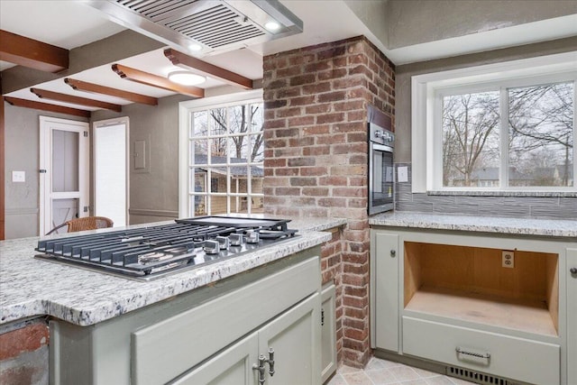 kitchen with stainless steel appliances, brick wall, light stone countertops, and a wealth of natural light