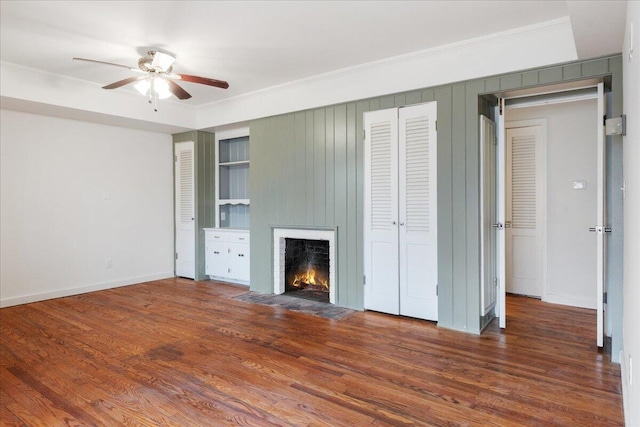 unfurnished living room featuring dark wood-type flooring, ceiling fan, and ornamental molding