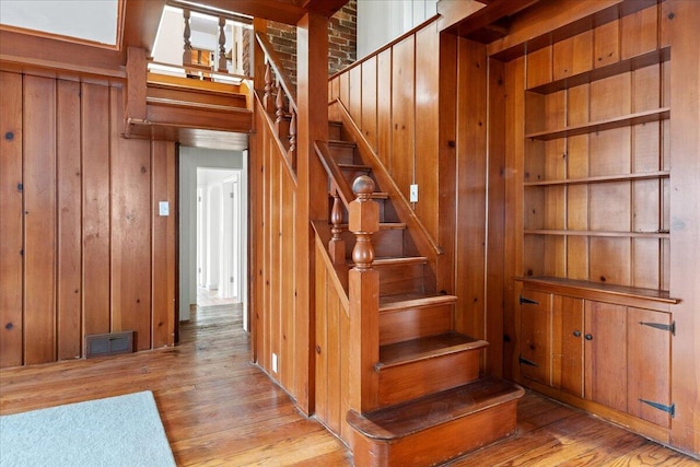 stairs with wooden walls and hardwood / wood-style floors