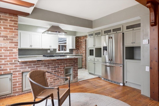 kitchen featuring sink, stainless steel fridge, light stone countertops, light hardwood / wood-style floors, and kitchen peninsula