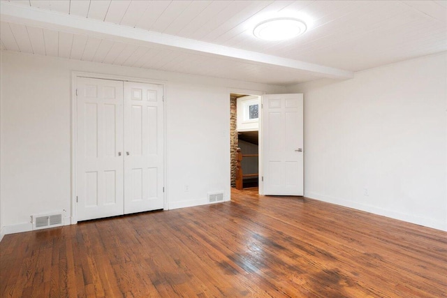 unfurnished bedroom featuring a closet, dark hardwood / wood-style floors, beam ceiling, and wooden ceiling