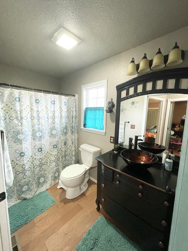 bathroom with vanity, toilet, hardwood / wood-style floors, and a textured ceiling