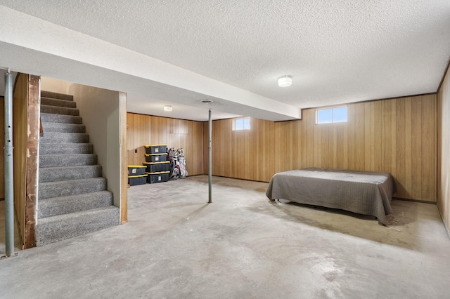 unfurnished bedroom with a textured ceiling and wooden walls