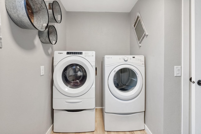 laundry area with washing machine and clothes dryer and light hardwood / wood-style flooring