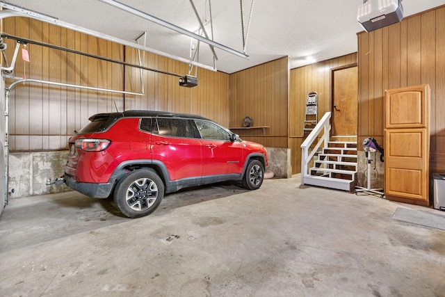 garage featuring a garage door opener and wooden walls