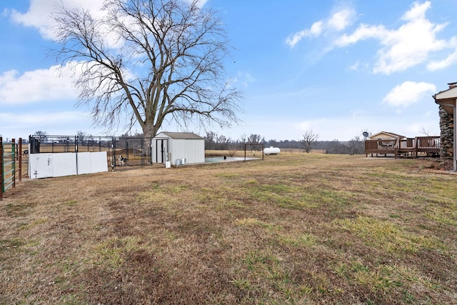 view of yard featuring a rural view, a deck, and a storage shed