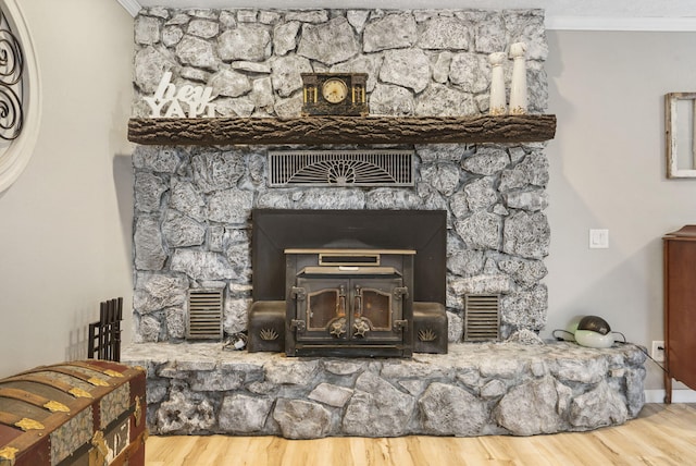 details with hardwood / wood-style flooring, ornamental molding, and a wood stove