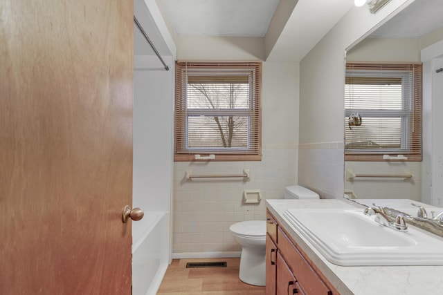 bathroom featuring hardwood / wood-style flooring, vanity, a wealth of natural light, and toilet