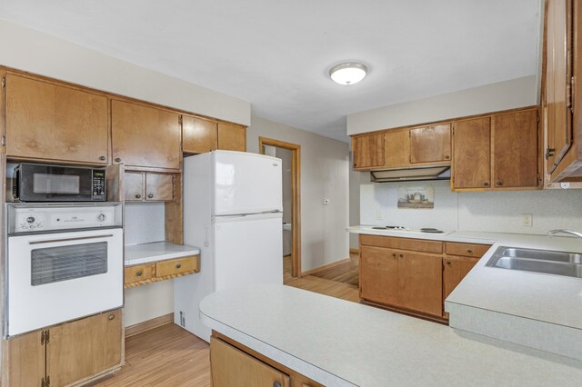 kitchen with white appliances, light hardwood / wood-style floors, and sink