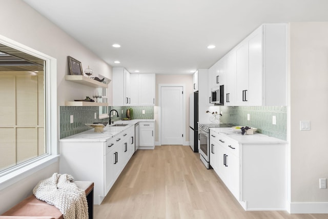 kitchen with sink, tasteful backsplash, light hardwood / wood-style flooring, stainless steel appliances, and white cabinets