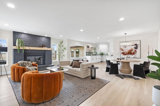 living room with a healthy amount of sunlight, sink, a fireplace, and light wood-type flooring